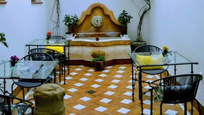 Un patio con piso de tablero de damas, una cama con cabecera de madera y una mesa con sillas.
