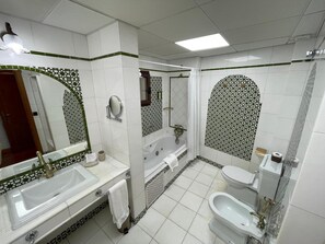 Un baño con un espejo grande, una bañera, un inodoro y un bidé.