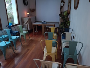Una habitación con suelo de madera, una mesa con sillas y una ventana que da a unas copas de árboles.