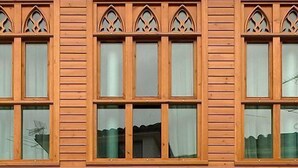 Une façade d’immeuble ornée de nombreuses fenêtres, caractérisée par des arcs brisés et des panneaux de bois.