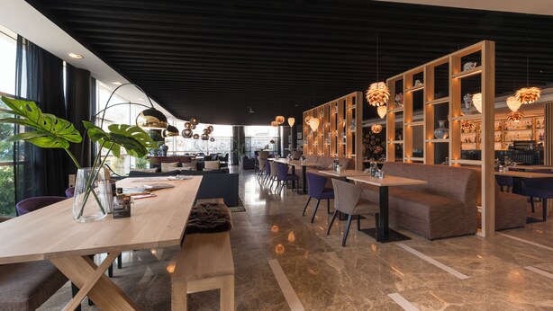 A modern interior with a long dining table, seating area, and a display of decorative items. - Shanghai Hotel Holland (Delft)