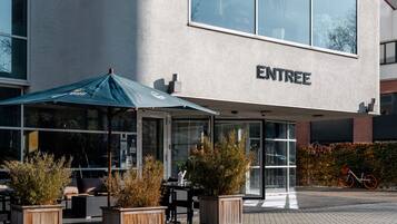 A building named 'ENTREE' with outdoor seating and potted plants.