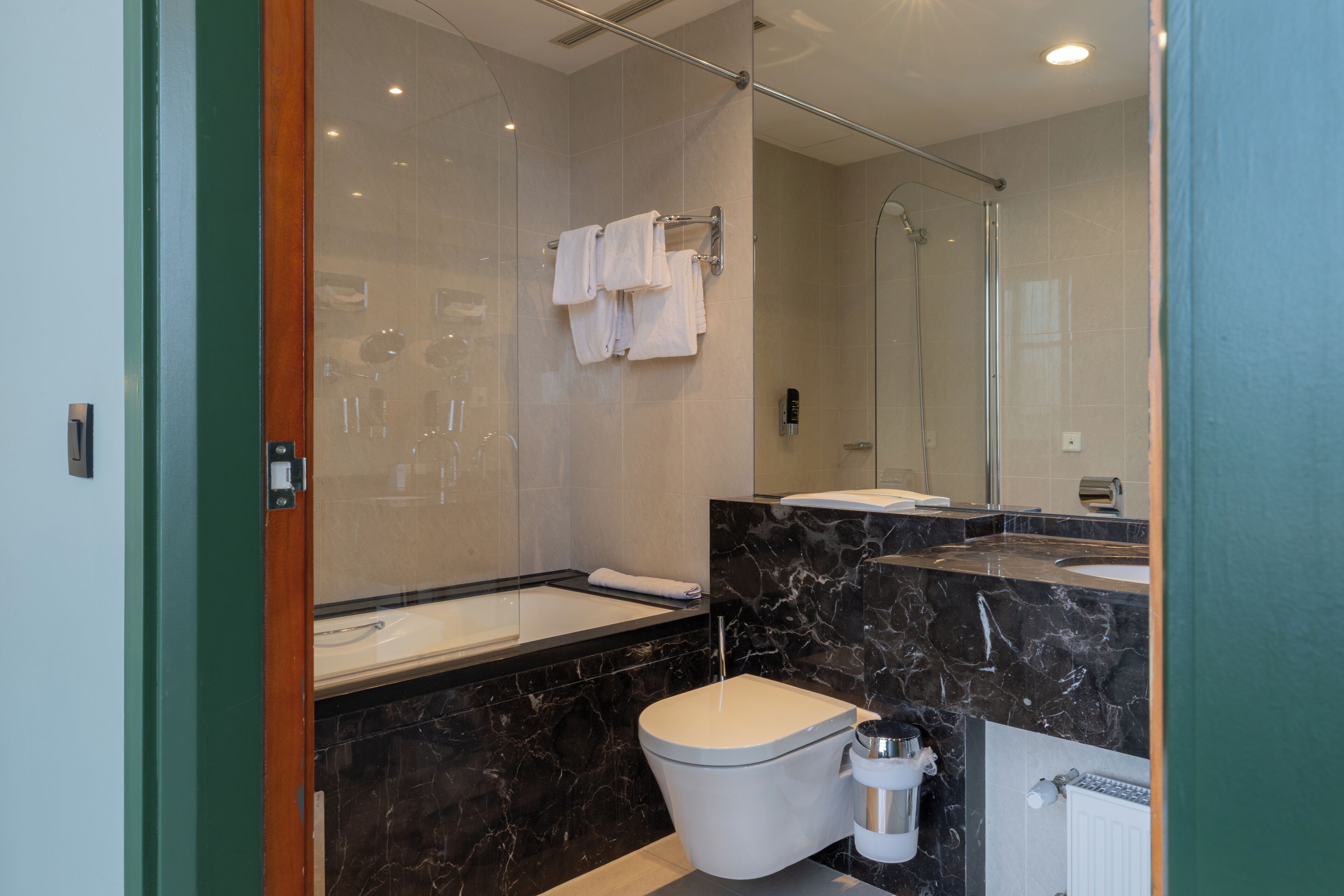 Ein modernes Badezimmer mit einer gläsernen Duschkabine, einem мраморным Waschbecken und einer Toilette.