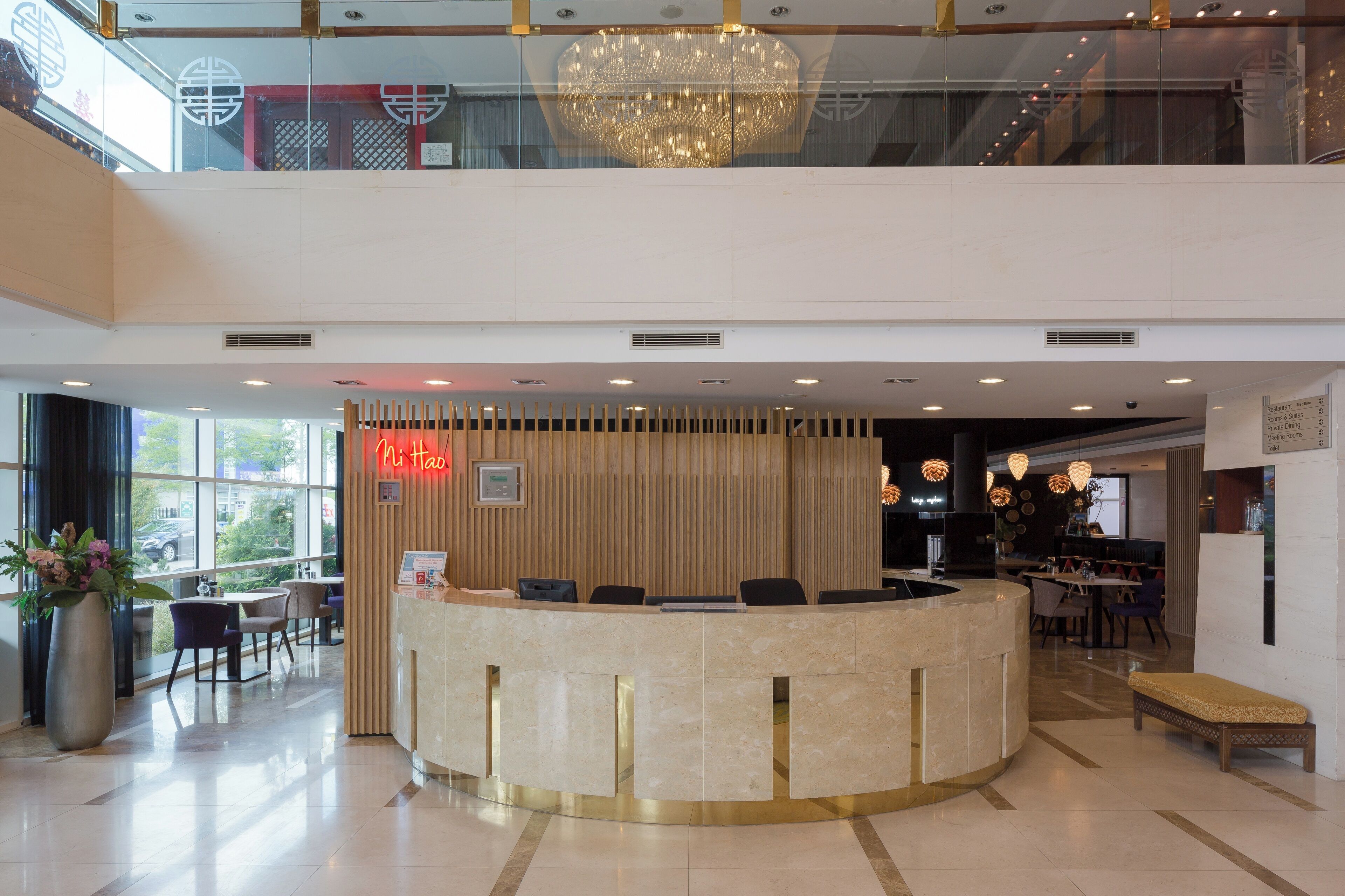 En hotellobby med en marmordisk, sittplatser, en kristallkrona och utsikt över omgivningarna.
