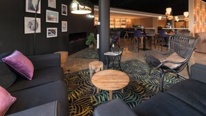 A modern lounge area with a sofa, chairs, a small table, and a patterned carpet. - Shanghai Hotel Holland (Delft)