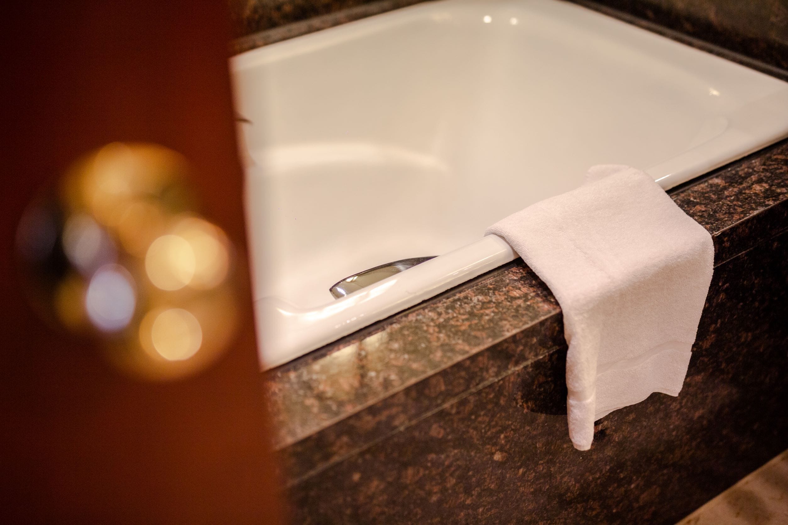 Un baño con una bañera blanca, una toalla blanca y una encimera de granito.