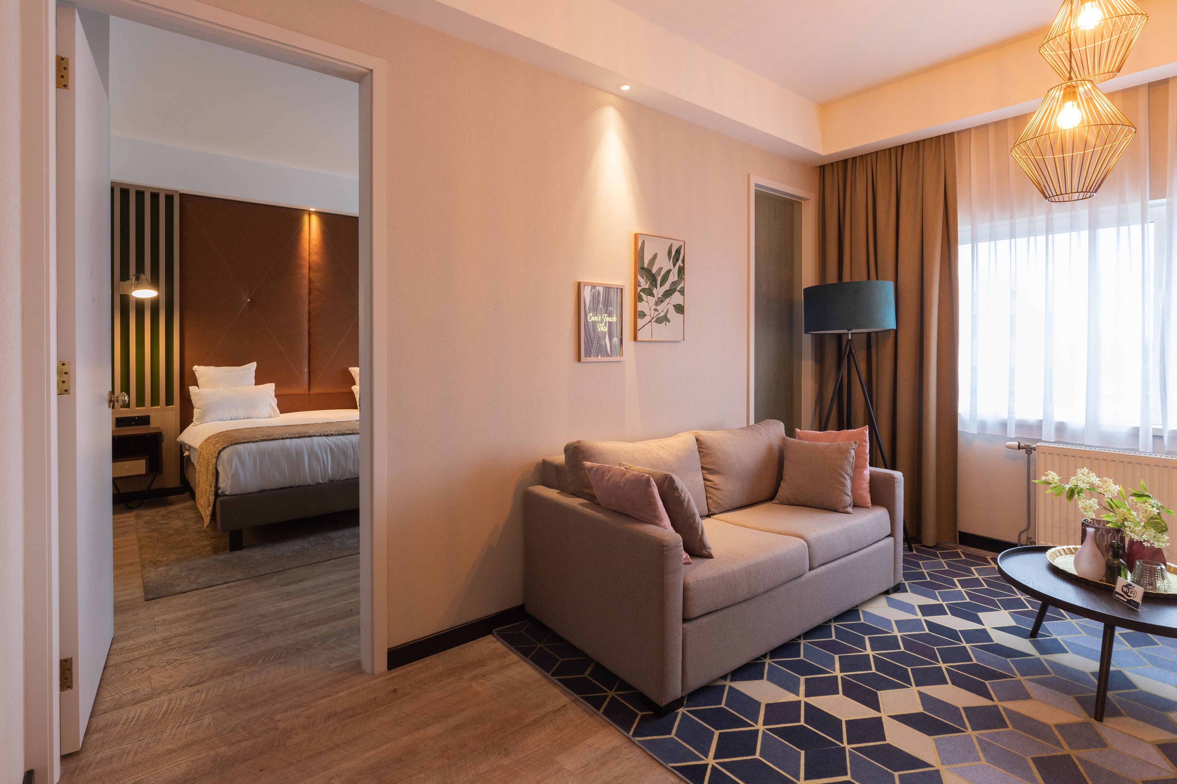 A hotel room with a bed, a sofa, a coffee table, and a lamp.