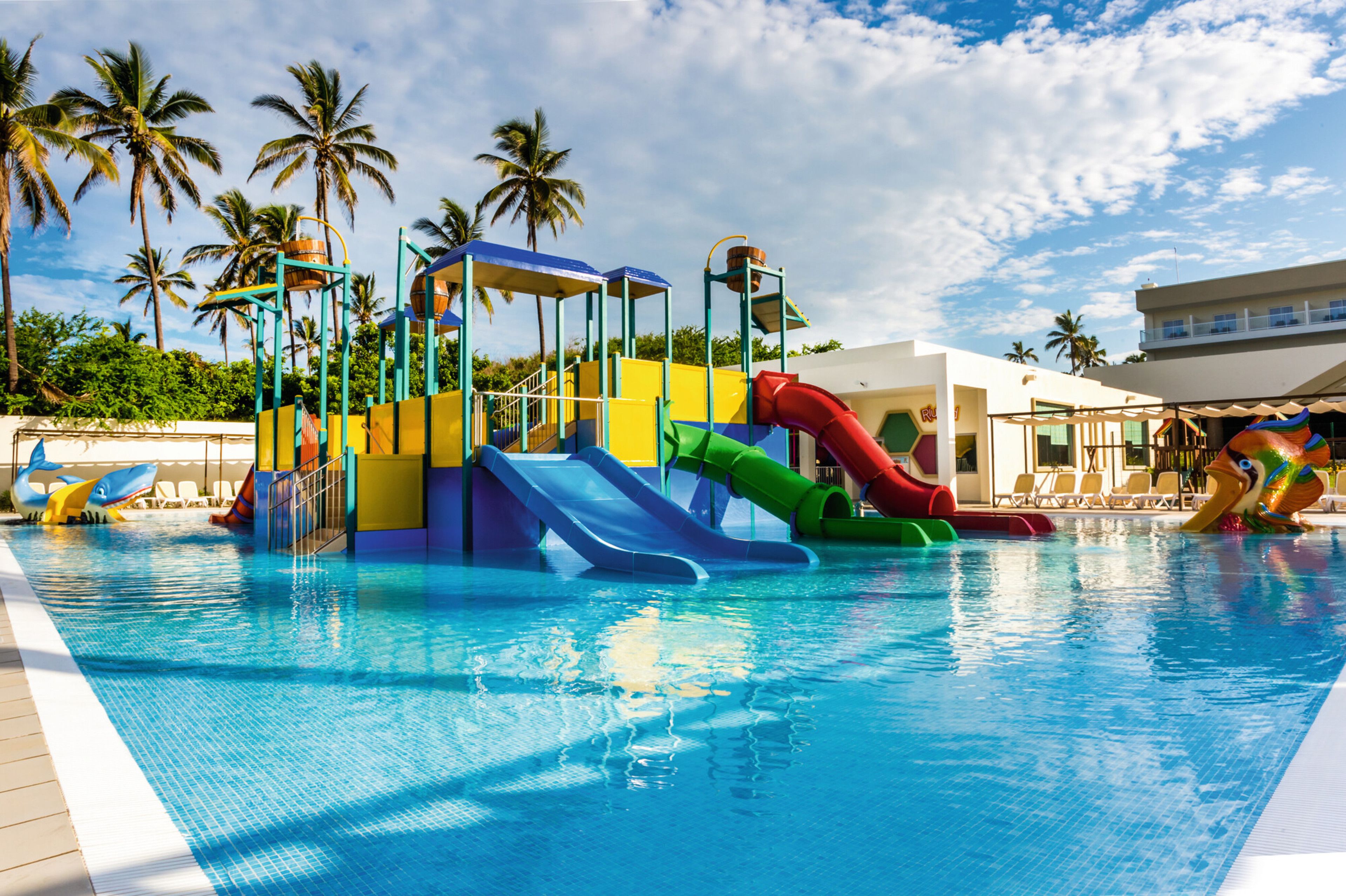 A swimming pool with multiple slides and a water play area.