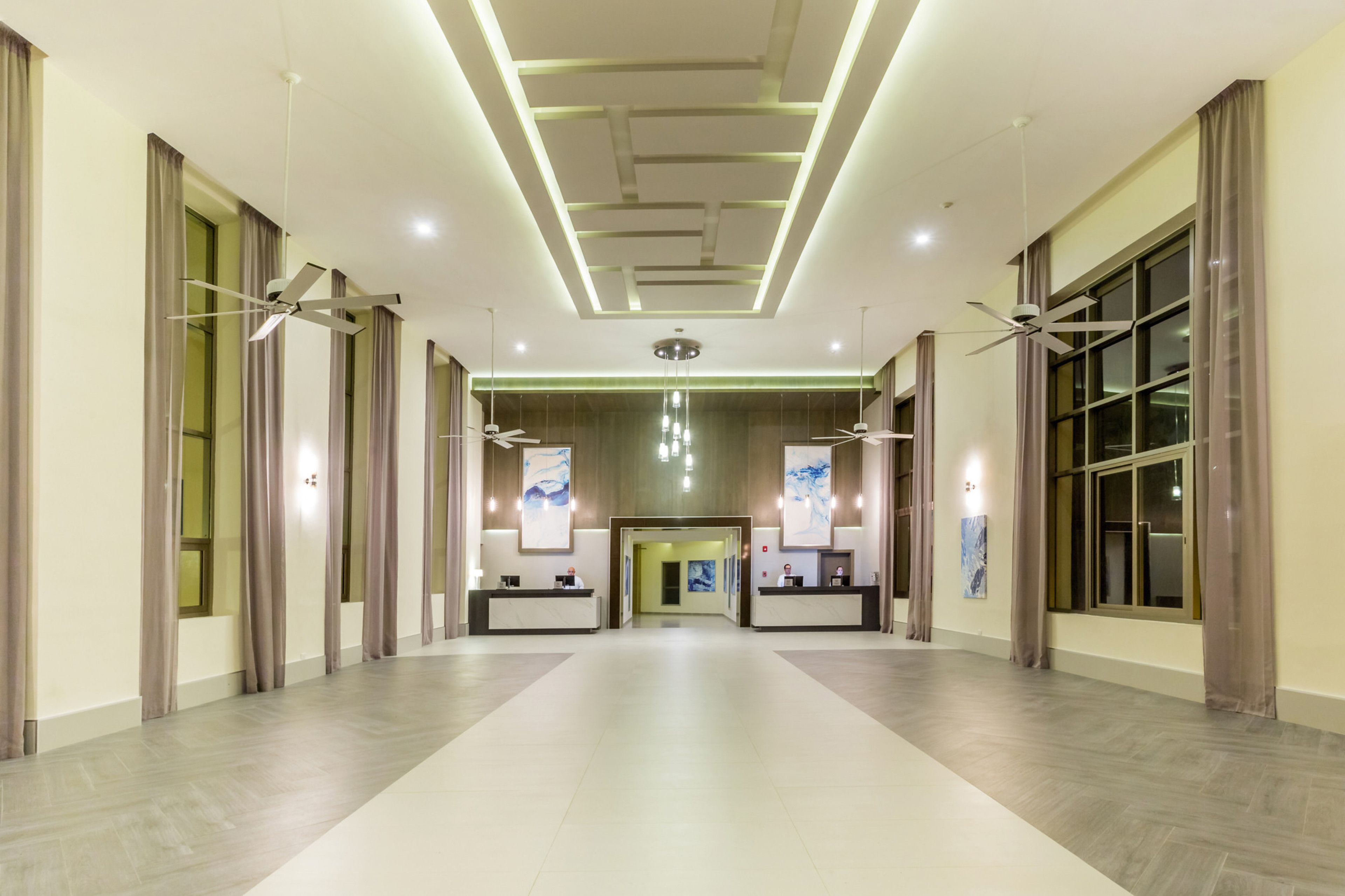 Un hall d’entrée spacieux, doté d’un plafond au design moderne, de deux comptoirs d’accueil et d’un lustre central.
