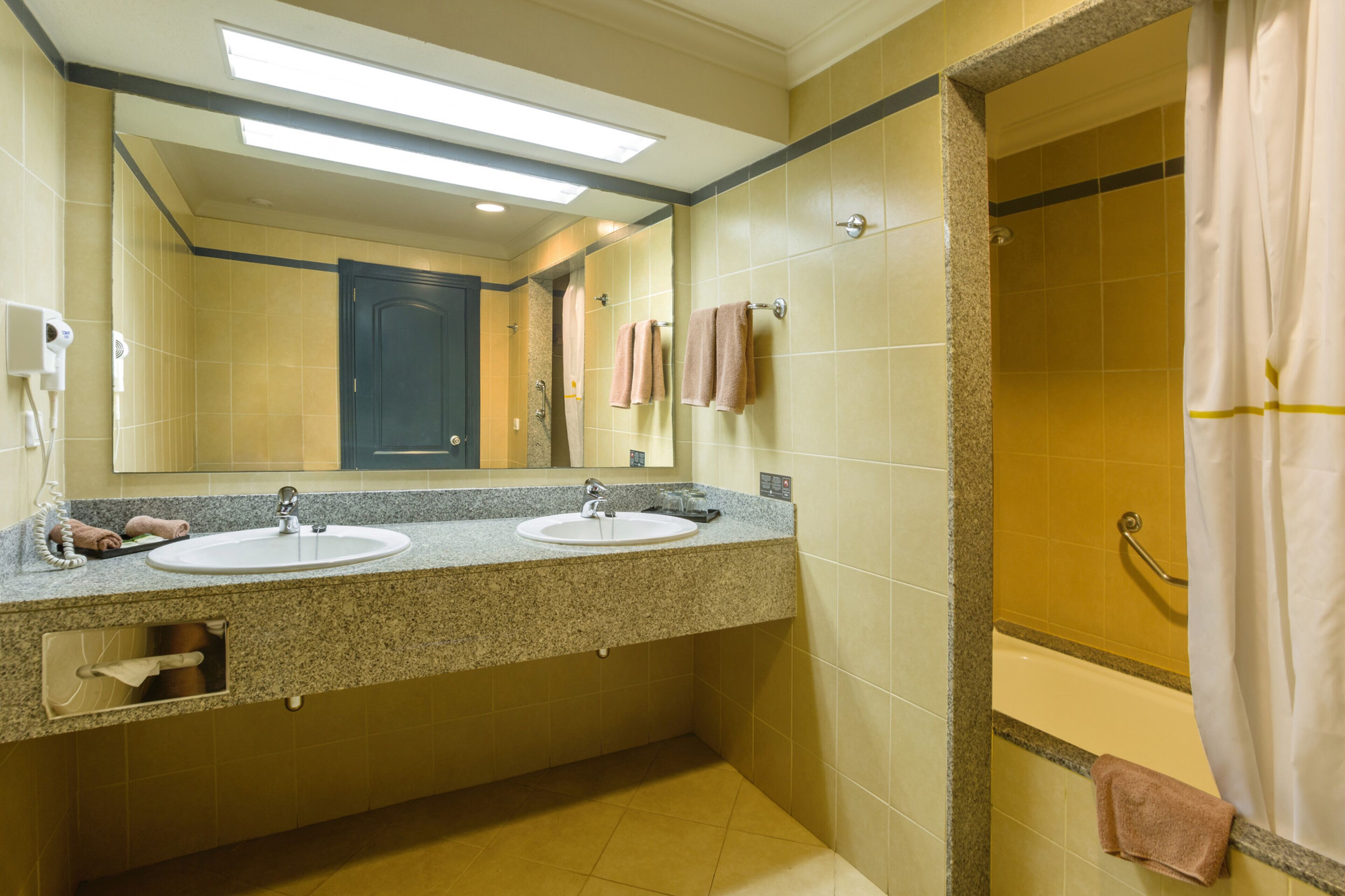 A bathroom with two sinks, a mirror, and a shower.
