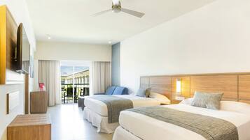 Habitación de hotel con dos camas, ventilador de techo, televisión y vistas al exterior.