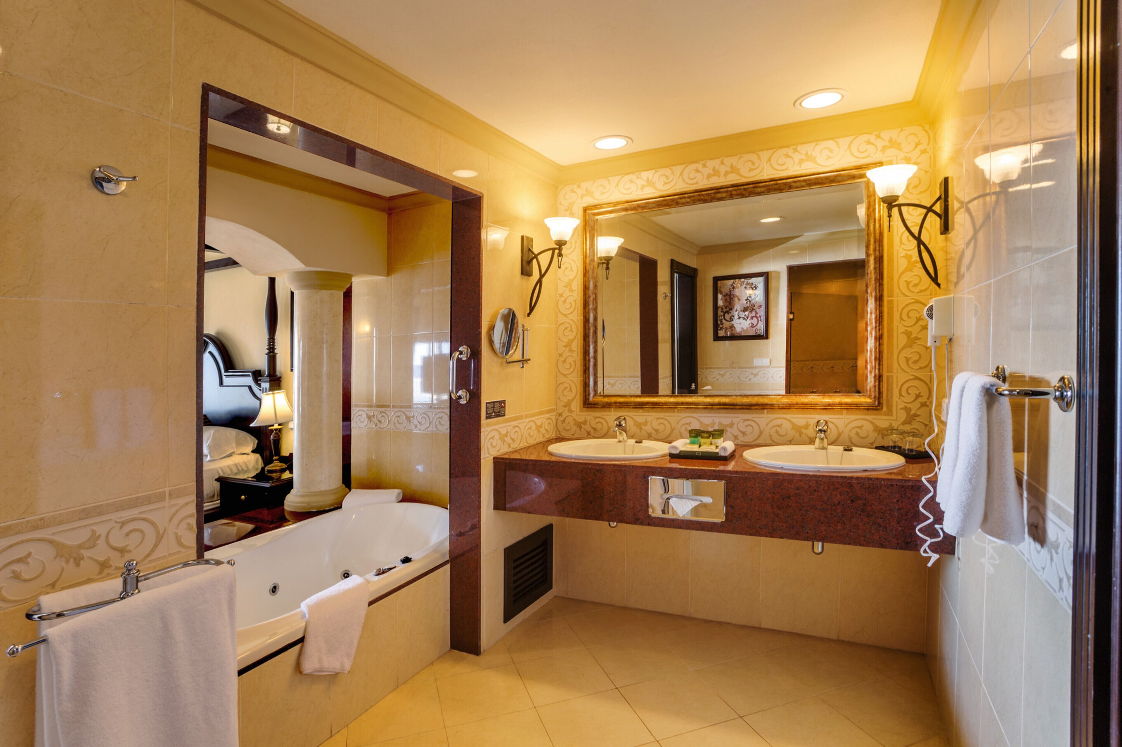 Une salle de bain avec une baignoire, deux lavabos, un grand miroir et un porte-serviettes.