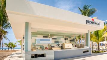 Un restaurant moderne en plein air, reconnaissable à son enseigne « pepe’sfood », qui propose un comptoir, un espace pour s’asseoir et une vue sur la plage.