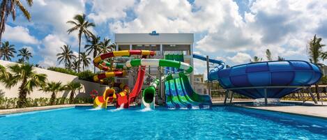 A swimming pool with multiple water slides and a building in the background.