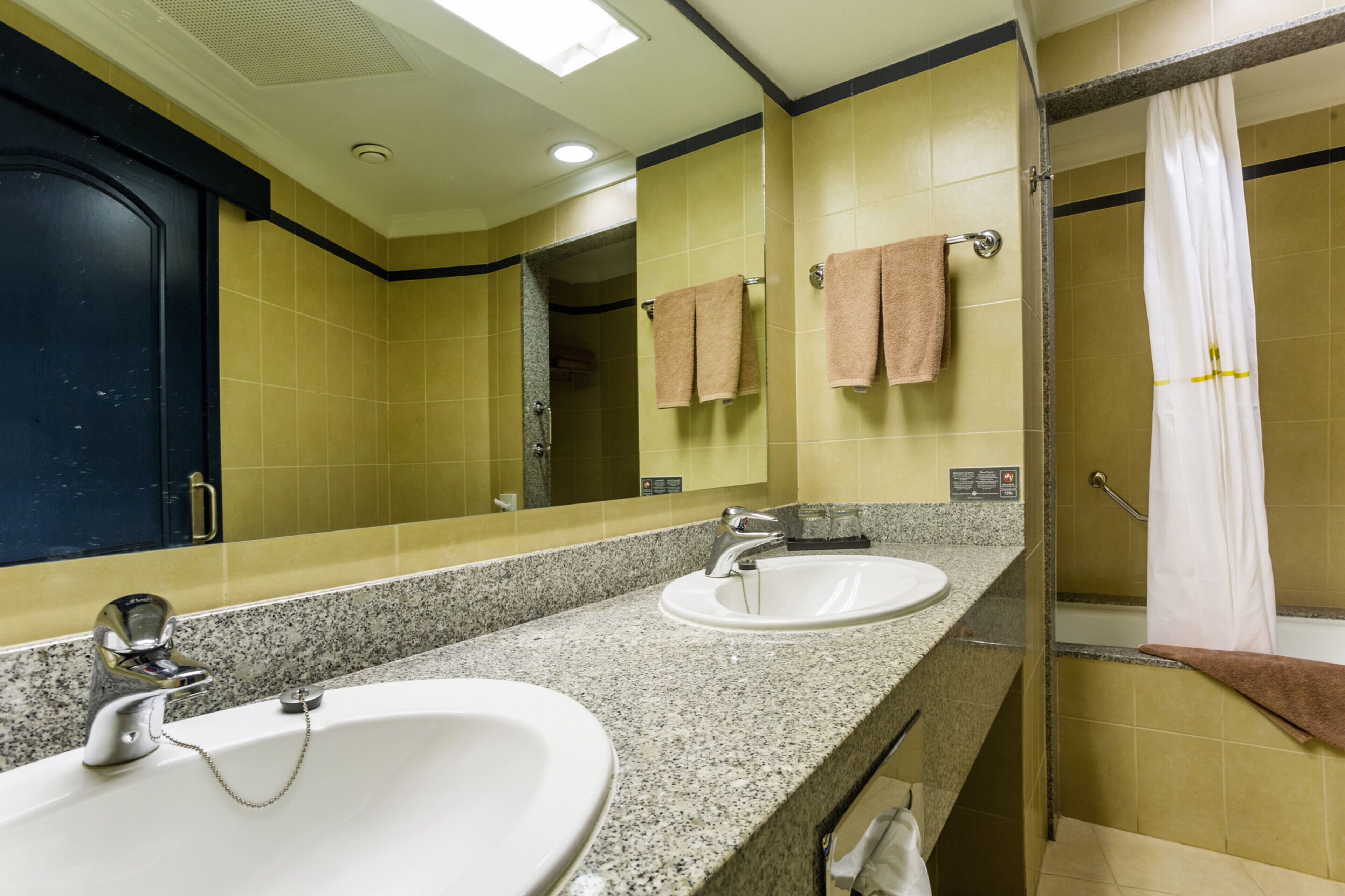 A bathroom with two sinks, a mirror, and a shower area.
