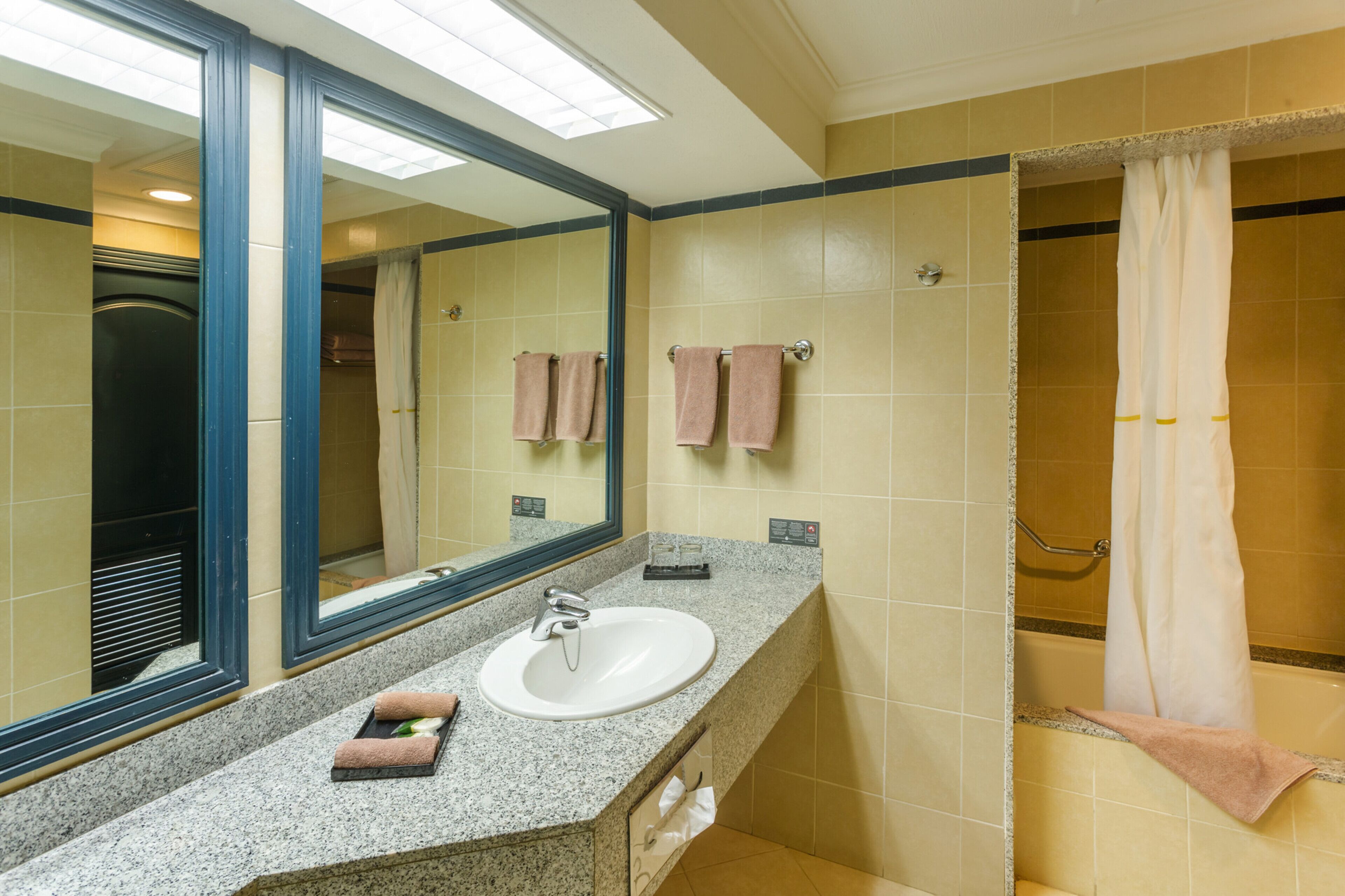 A bathroom with a sink, mirror, and shower area.