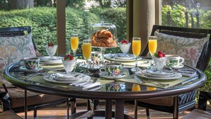 A breakfast table set with plates, cups, and glasses, surrounded by chairs with floral upholstery. - Stonehurst Place Bed & Breakfast (Atlanta)