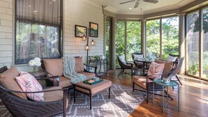A sunlit room with wicker furniture, large windows, and a ceiling fan. - Stonehurst Place Bed & Breakfast (Atlanta)