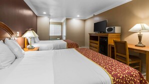 A hotel room with two beds, a desk, a television, and a microwave. - Rodeway Inn Cypress - Buena Park (Cypress)