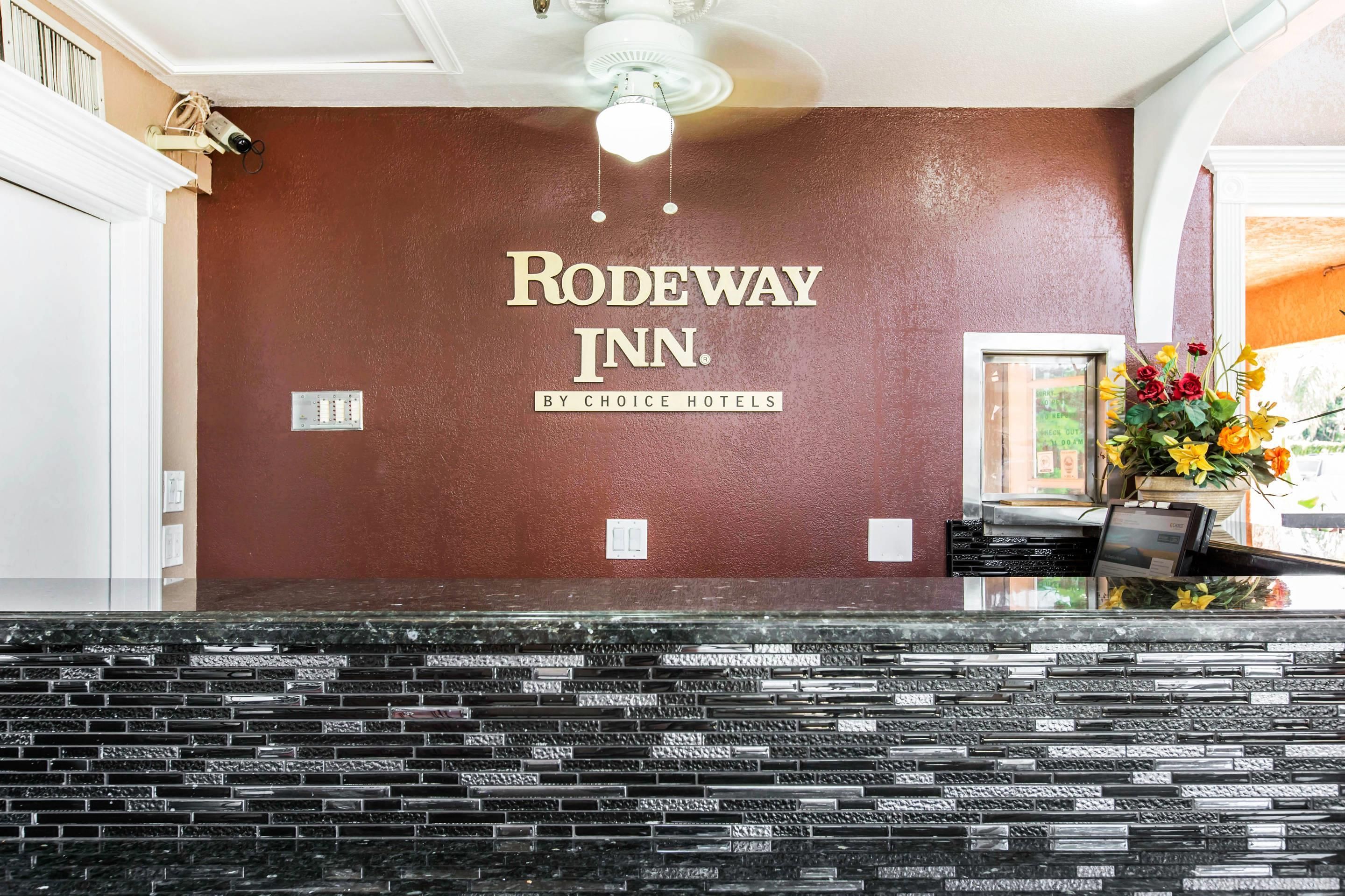 A reception area with a brown textured wall, a ceiling fan, and a reception desk with a vase of flowers.