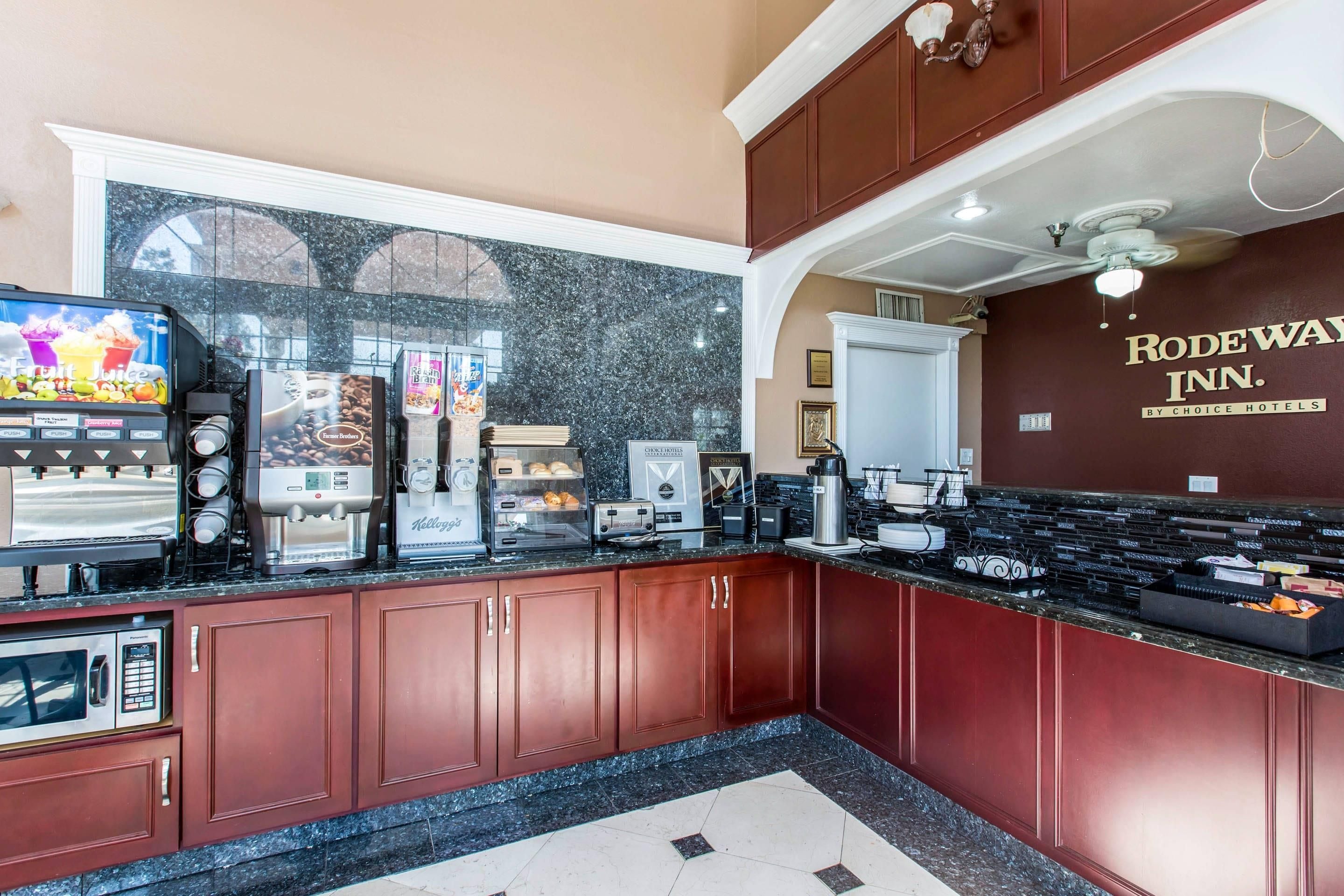 A hotel kitchen with a coffee station, a refrigerator, and a wall with the hotel name.