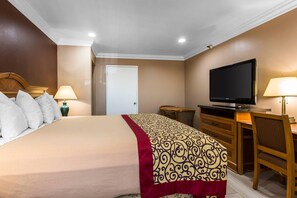 A hotel room with a bed, a television, a desk, and a chair. - Rodeway Inn Cypress - Buena Park (Cypress)