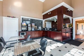 A modern kitchen with a dining area, equipped with a coffee machine, microwave, and toaster. - Rodeway Inn Cypress - Buena Park (Cypress)