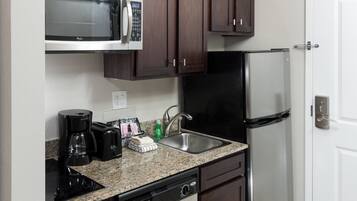 A compact kitchen with a microwave, coffee maker, toaster, sink, and dishwasher.