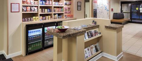 A snack bar with shelves of snacks and a refrigerator.