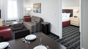 Une chambre d’hôtel comprenant un coin repas, un canapé, un lit et une petite table avec une lampe.