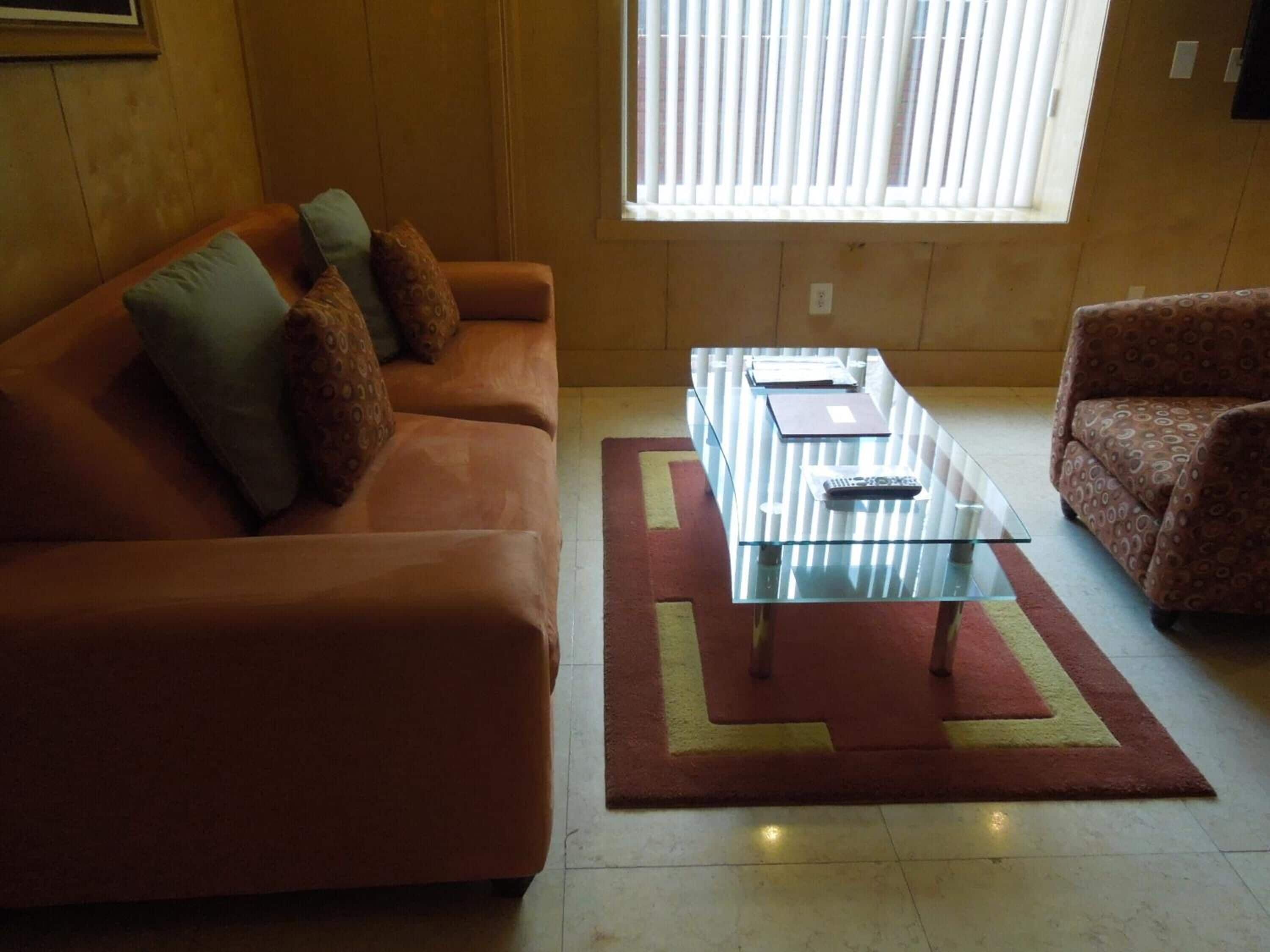 Een woonkamer met een bank, fauteuil en glazen salontafel.