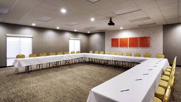 A conference room with a long table, yellow chairs, and a carpeted floor.