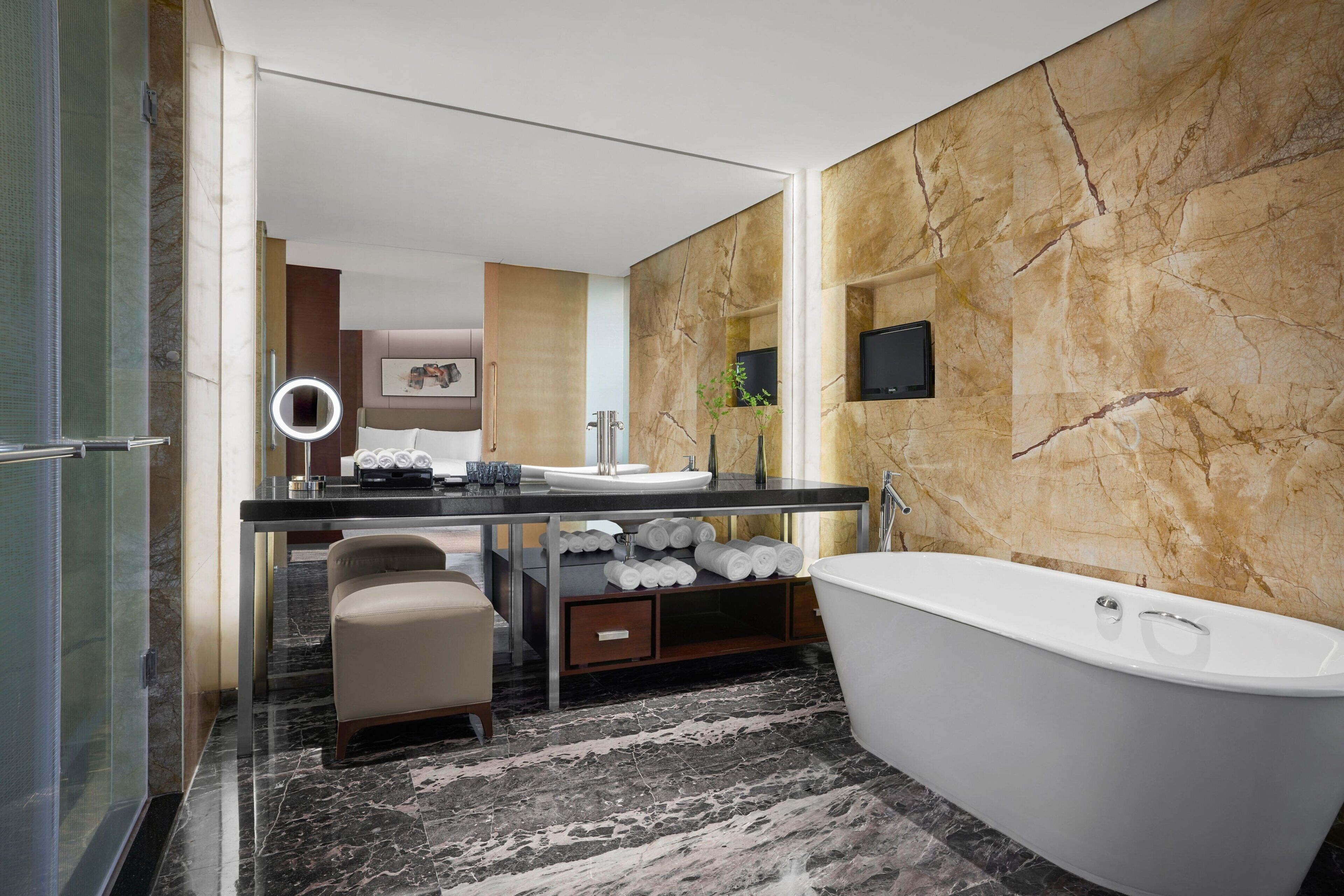 Un bagno moderno con pavimento in marmo, una vasca da bagno indipendente, un mobile lavabo con specchio e un water.
