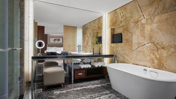 Un bagno moderno con pavimento in marmo, una vasca da bagno indipendente, un mobile lavabo con specchio e un water.