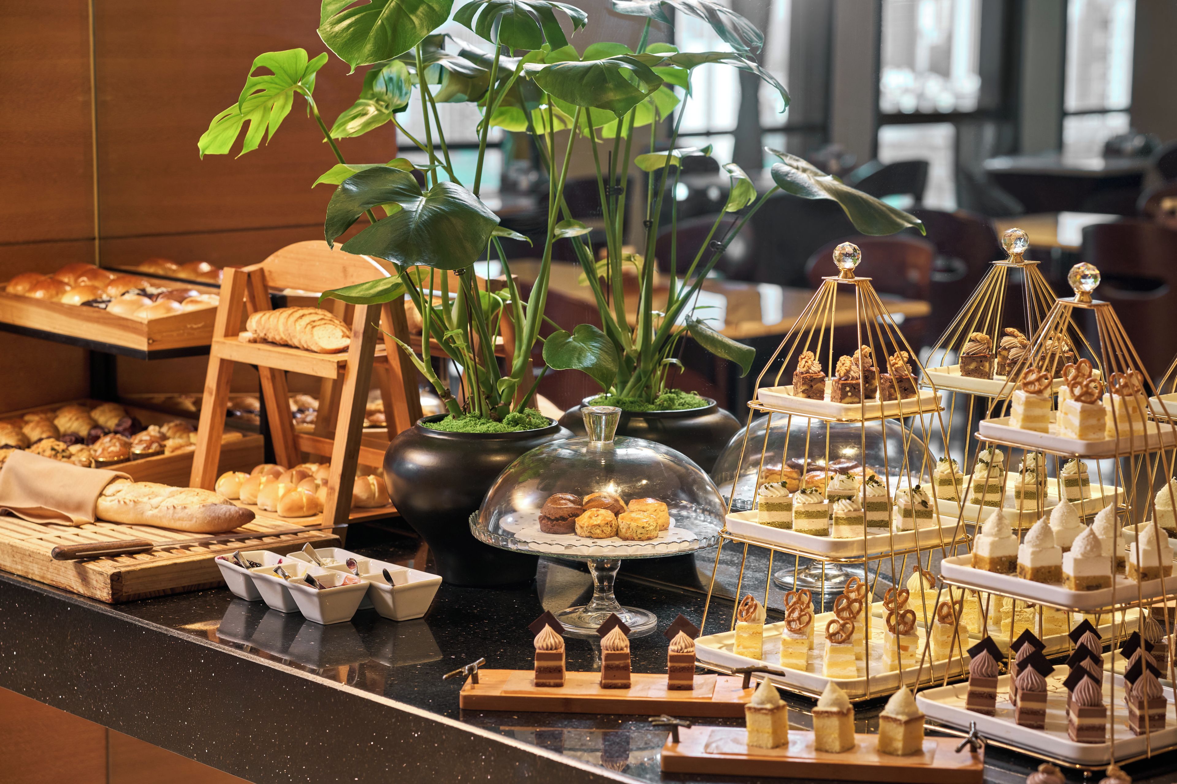 A buffet with various pastries, desserts, and bread displayed on a counter.