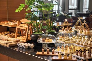 A buffet with various pastries, desserts, and bread displayed on a counter. - JW Marriott Hotel Shenzhen (Shenzhen)