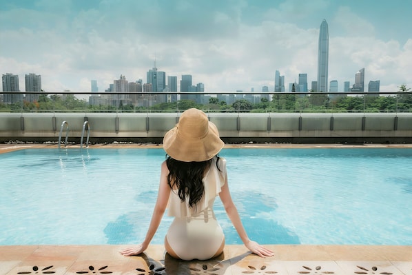 A person sitting by a pool with a city skyline in the background. - JW Marriott Hotel Shenzhen (Shenzhen)