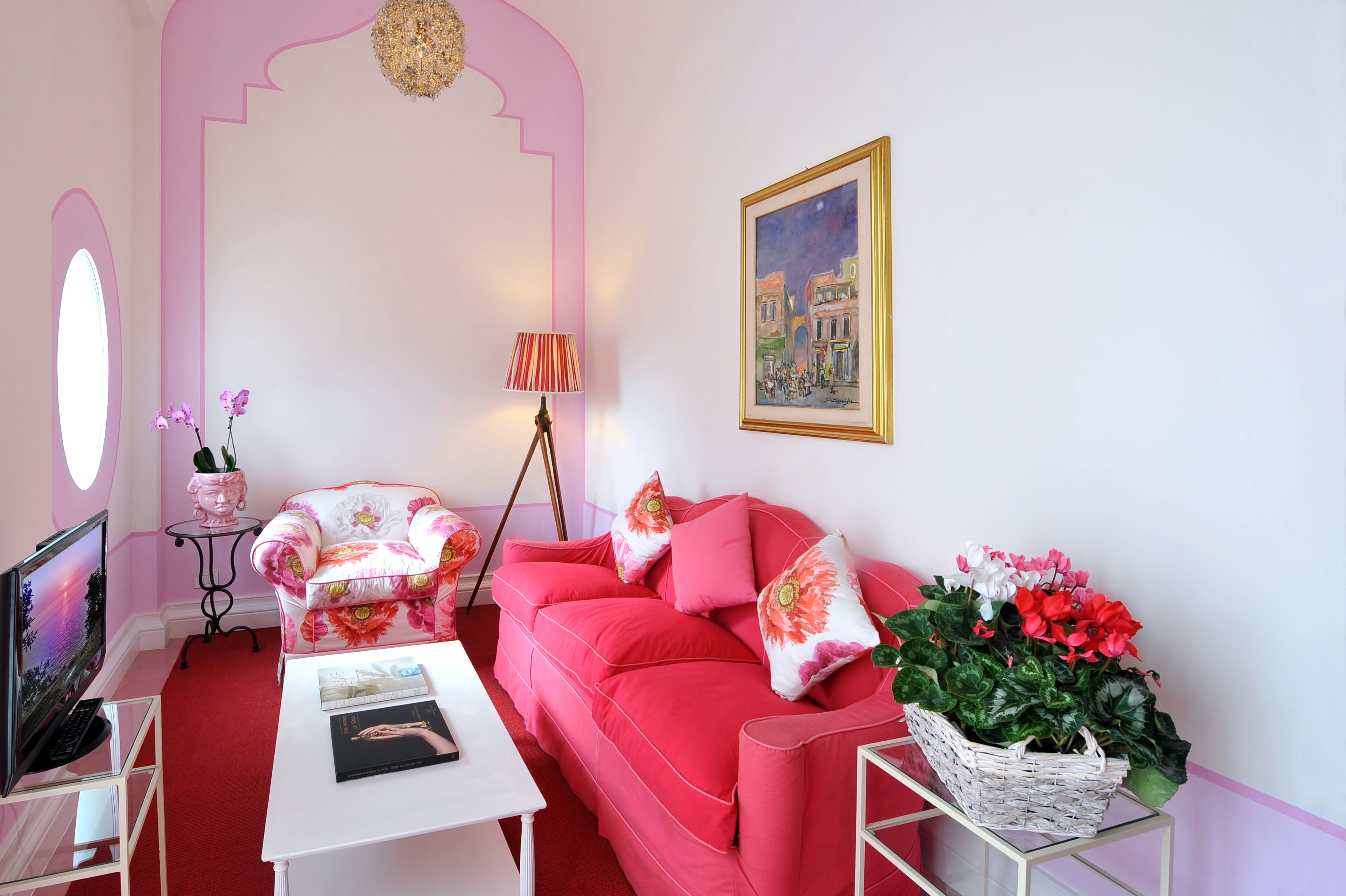 A pink-themed living room with a sofa, armchair, and a TV on a stand.