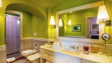 A bathroom with a large mirror, two toilets, a sink, and a vanity with drawers.