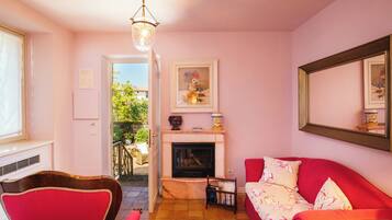 Una sala de estar con chimenea, sofá rojo y un comedor con una silla roja.