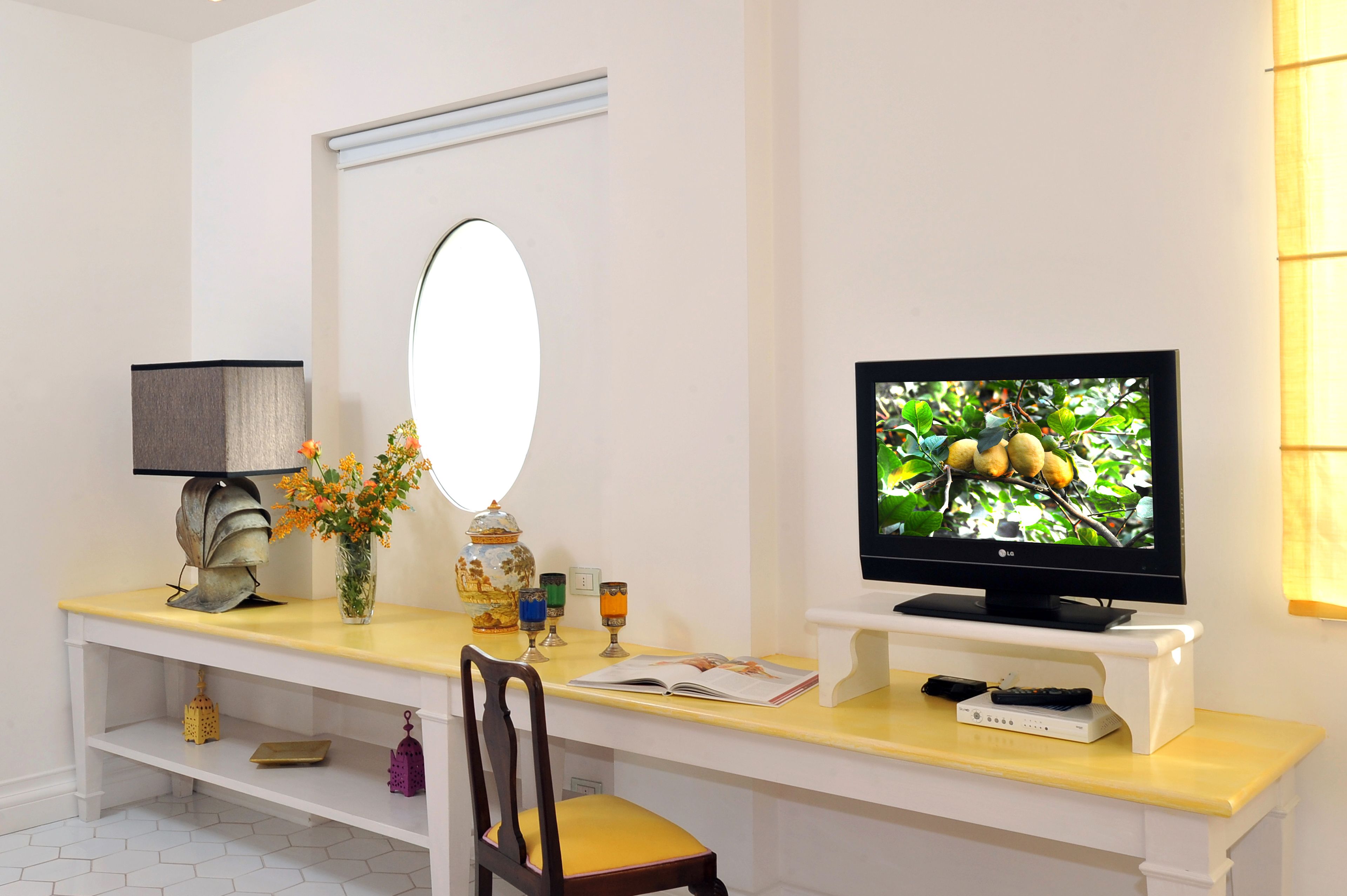 A modern living room with a TV, a large mirror, a desk, and a chair.