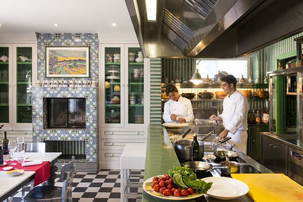 A modern kitchen with a checkered floor, a green and white tiled backsplash, and a large painting above the stove. - Boutique Hotel Ristorante Don Alfonso 1890 (Massa Lubrense)