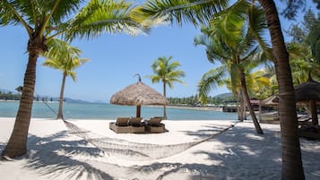 Een privéstrand, ligstoelen aan het strand, parasols, strandlakens