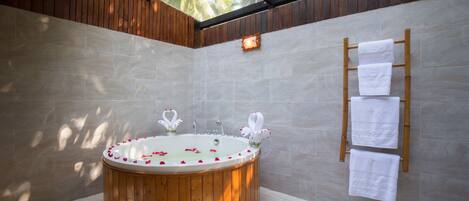 Un baño moderno con una bañera de madera, techo de cristal y un toallero de pared.