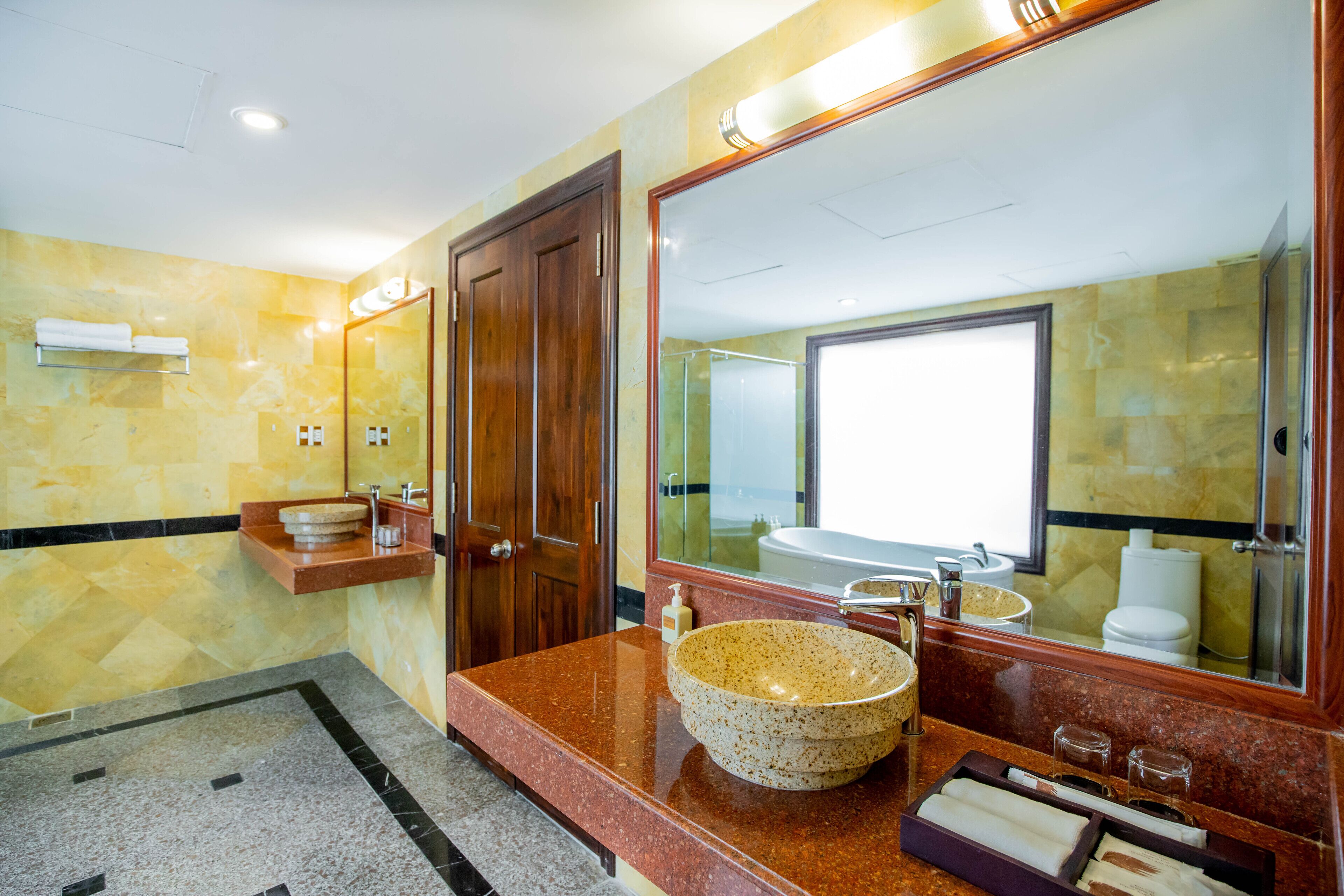 A modern bathroom with a large mirror, a granite countertop, and a large sink.