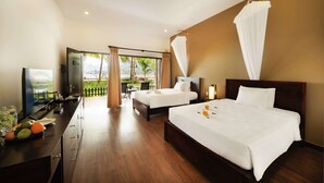 A hotel room with two beds, a TV, a desk with a computer, and a view of the outdoors. - Diamond Bay Resort and Spa (Nam Nha Trang)