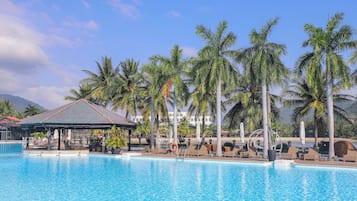 Una piscina al aire libre, sombrillas, sillones reclinables de piscina