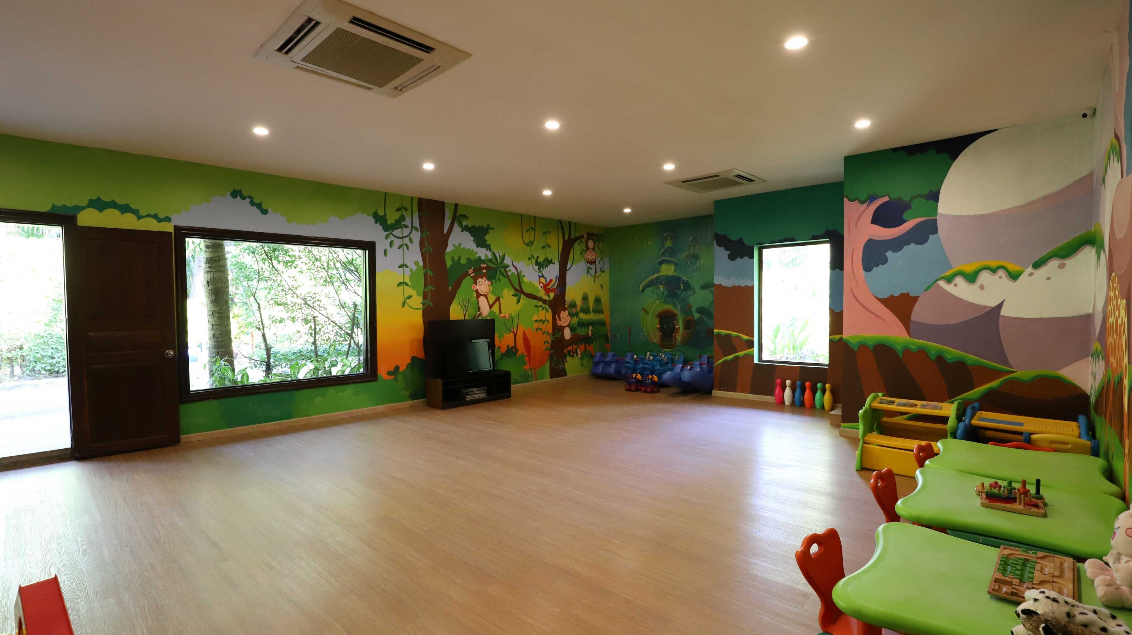 A children's playroom with a large window, a television, and colorful wall murals.