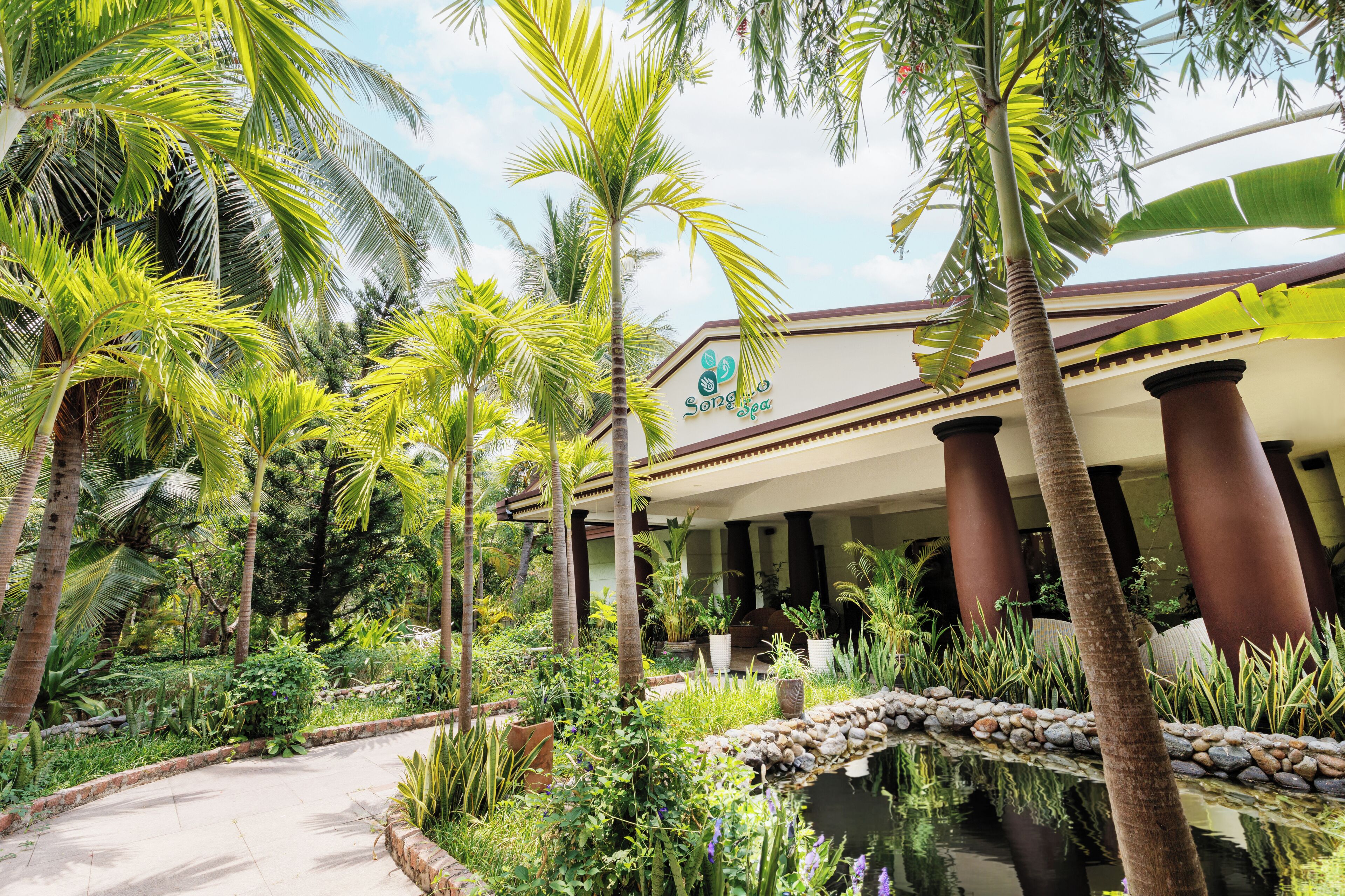 A resort with a pool, palm trees, and a building with columns.