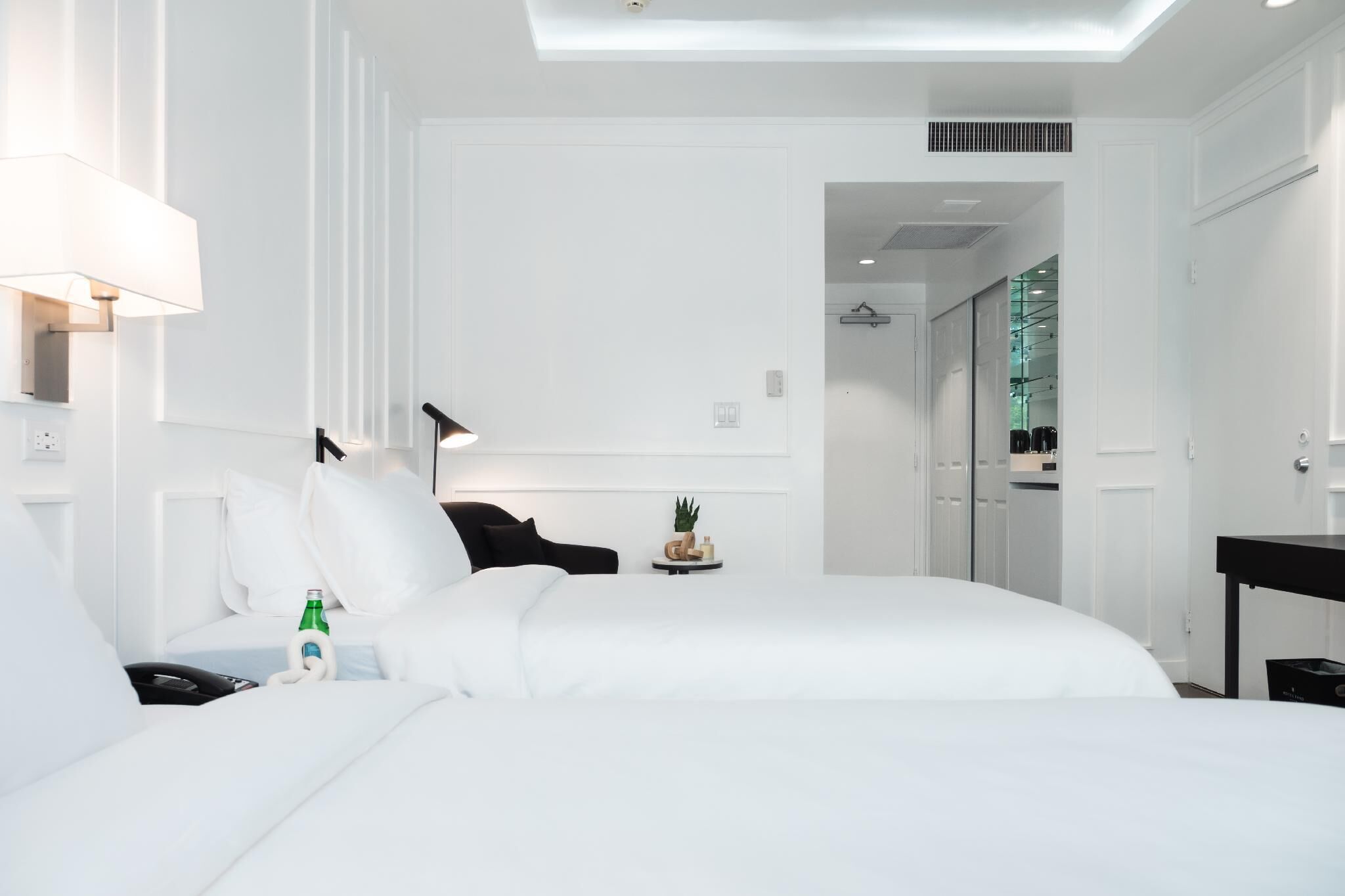 Una habitación de hotel moderna con una cama grande, mesitas de noche, un escritorio y una lámpara.